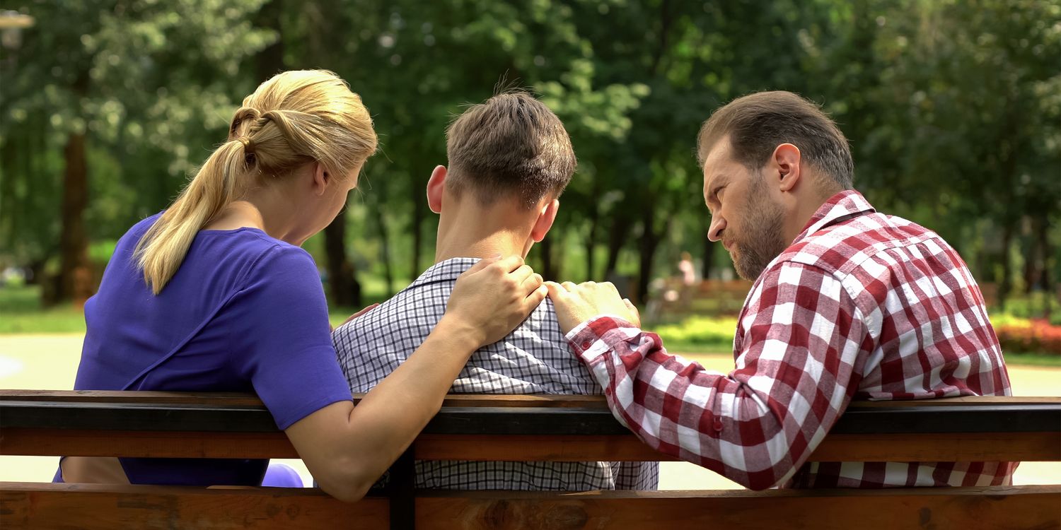 Hilfsangebote Eltern sitzen verzweifelt mit Sohn auf Bank im Park