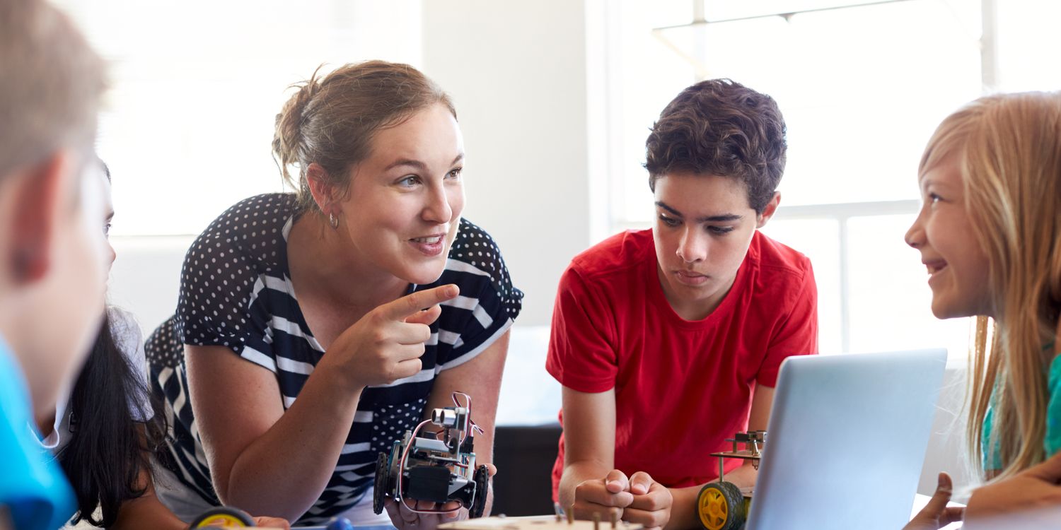 Team Junge Lehrerin erklärt Schülern einen Roboter